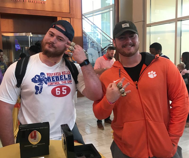 Two former athletes showing national championship rings