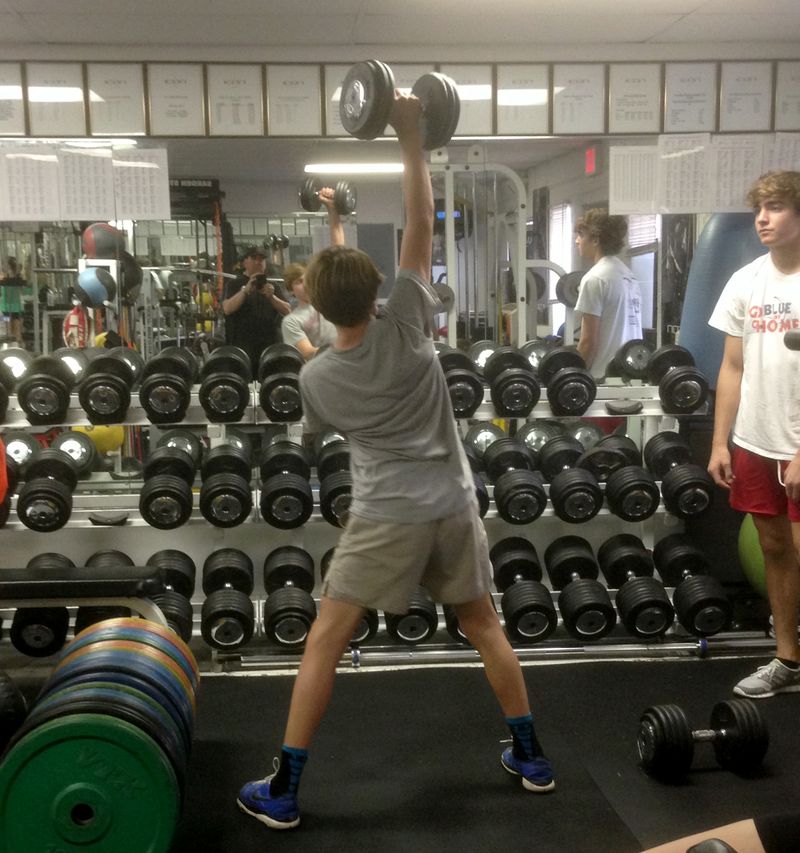 Young athlete performing a single-arm overhead dumbbell lift