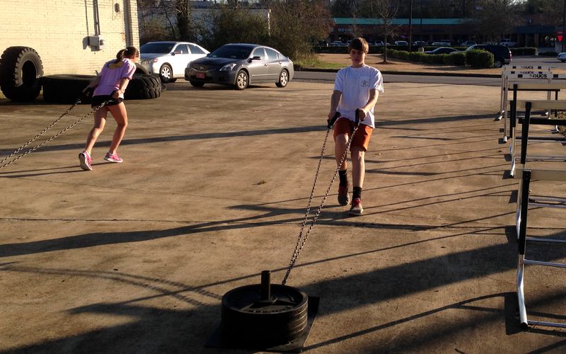 Youth athletes doing chain sled pulls outdoors